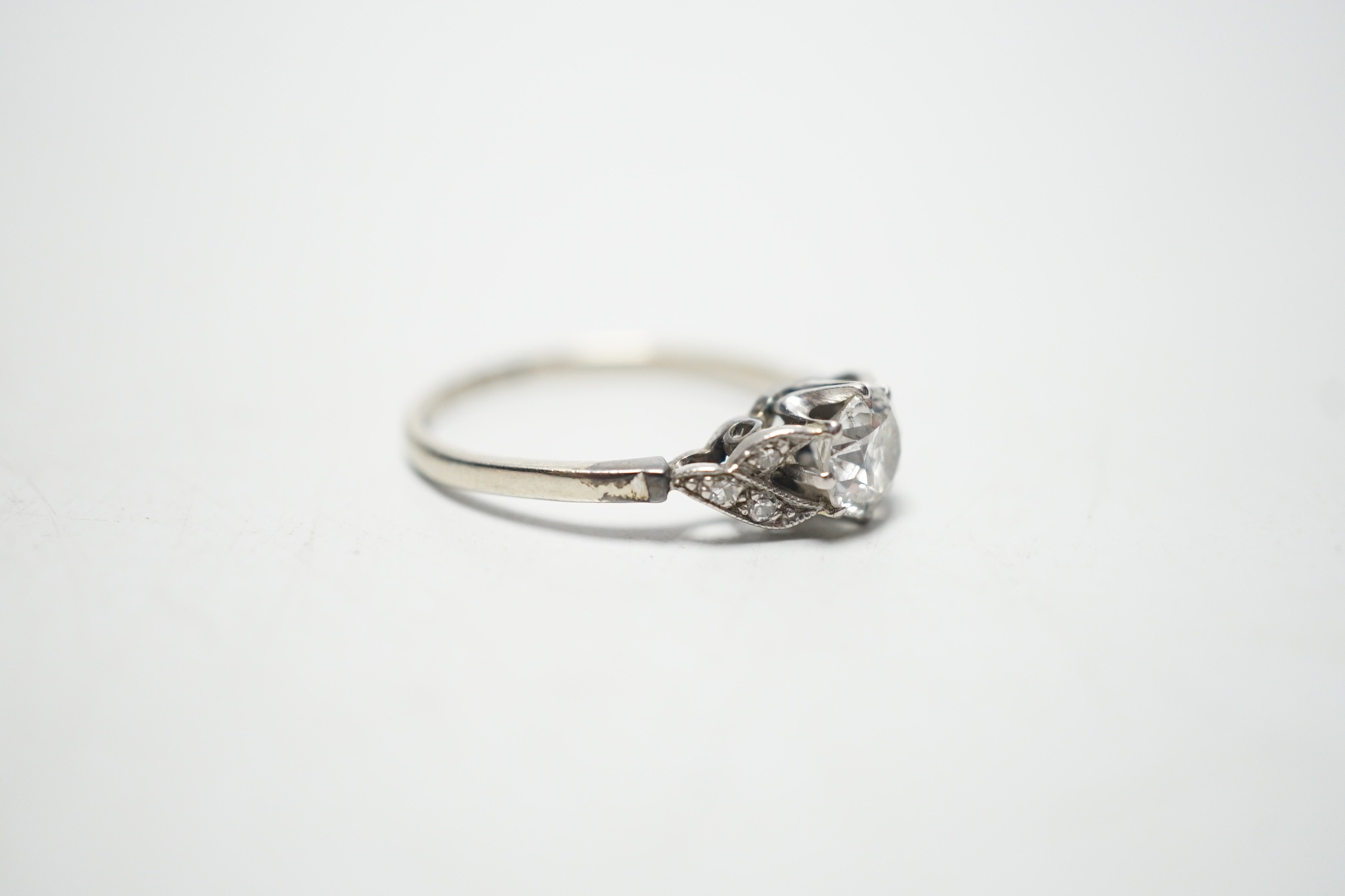 An 18ct white metal and single stone diamond ring, with diamond chip set shoulders, the stone weighing approximately 0.60ct, size M, gross weight 1.8 grams.